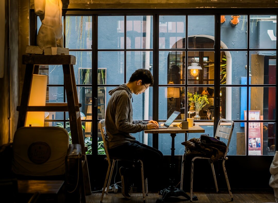 Person reading news on a laptop at a cafe table